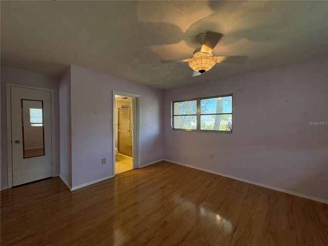 unfurnished bedroom featuring connected bathroom, hardwood / wood-style floors, a textured ceiling, and ceiling fan