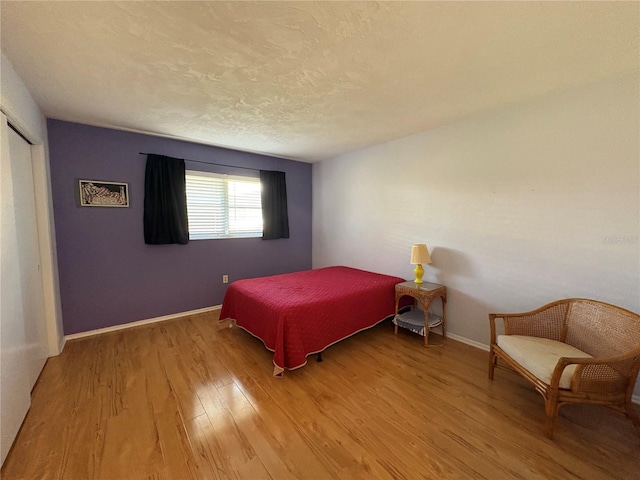 bedroom featuring a closet, light hardwood / wood-style floors, and a textured ceiling