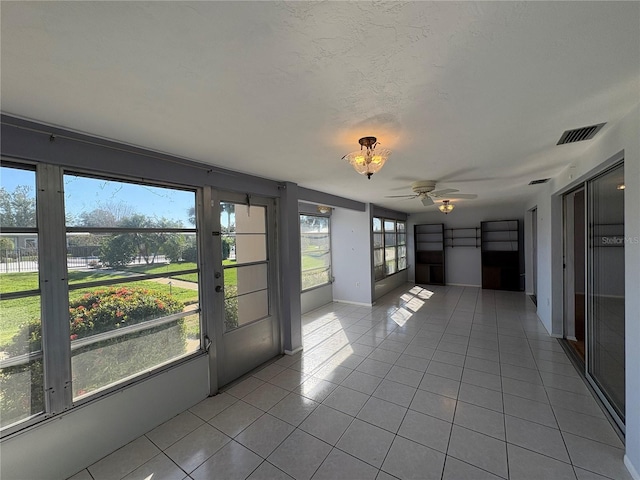 unfurnished sunroom with ceiling fan