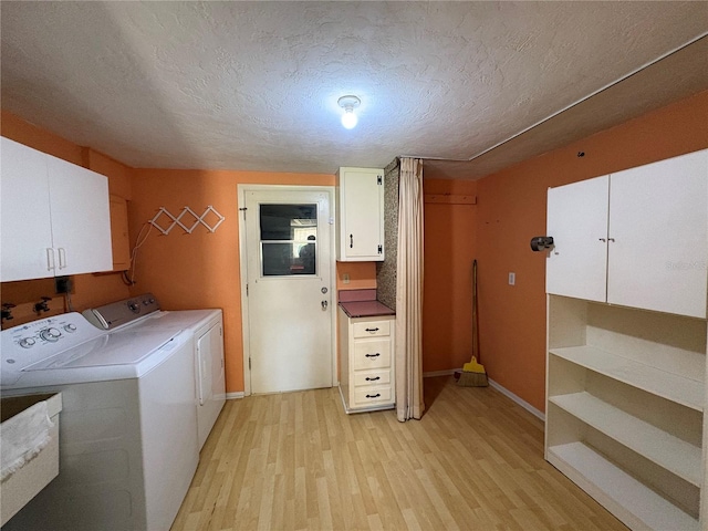 clothes washing area featuring washer and dryer, cabinets, a textured ceiling, and light wood-type flooring