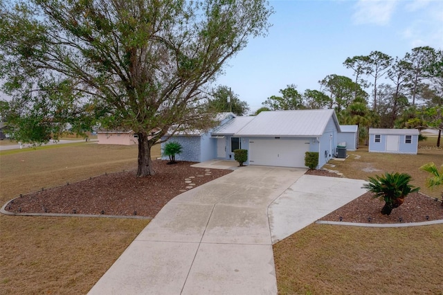 ranch-style house featuring a garage, a storage unit, cooling unit, and a front lawn