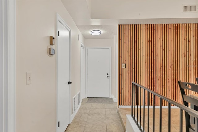 hall featuring light tile patterned floors and a textured ceiling