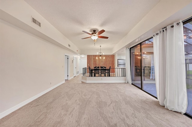 unfurnished living room featuring ceiling fan with notable chandelier, light colored carpet, a textured ceiling, and wood walls