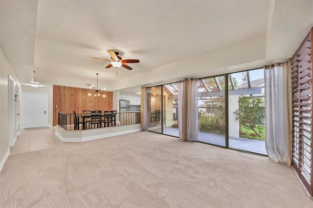 unfurnished living room with ceiling fan with notable chandelier, light colored carpet, a textured ceiling, and wood walls