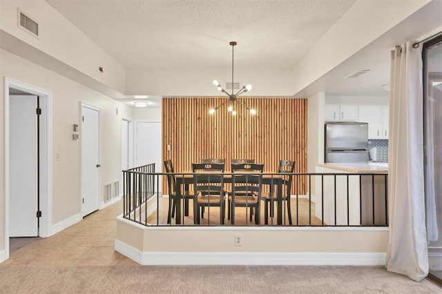 tiled dining room with a notable chandelier and a textured ceiling