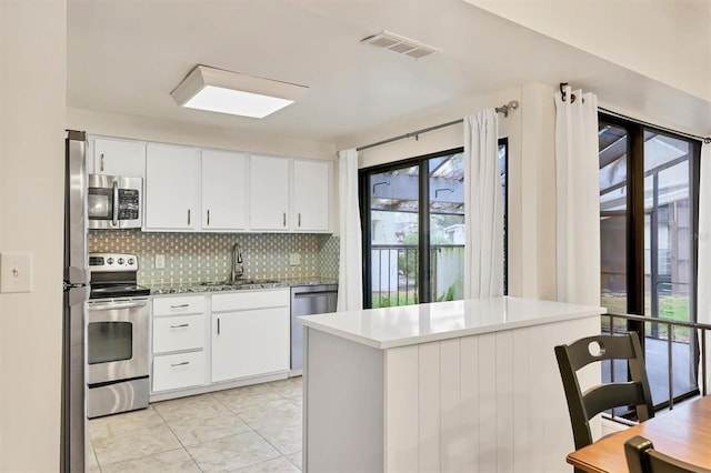 kitchen with stainless steel appliances, white cabinetry, sink, and backsplash