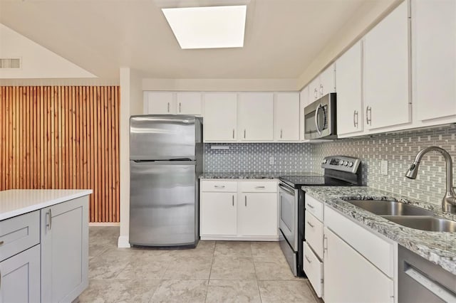 kitchen with sink, light stone counters, stainless steel appliances, decorative backsplash, and white cabinets