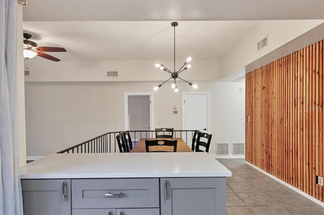 kitchen with ceiling fan with notable chandelier, gray cabinetry, pendant lighting, and light tile patterned floors