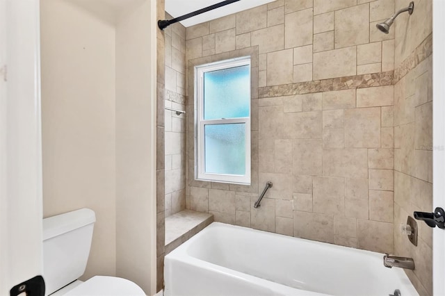 bathroom featuring tiled shower / bath combo and toilet