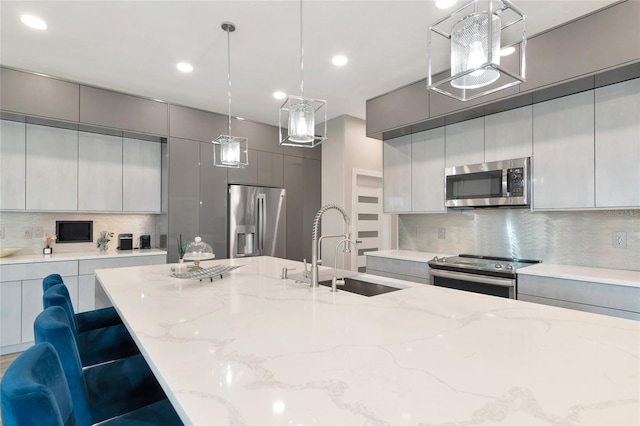 kitchen featuring sink, decorative light fixtures, gray cabinets, and stainless steel appliances