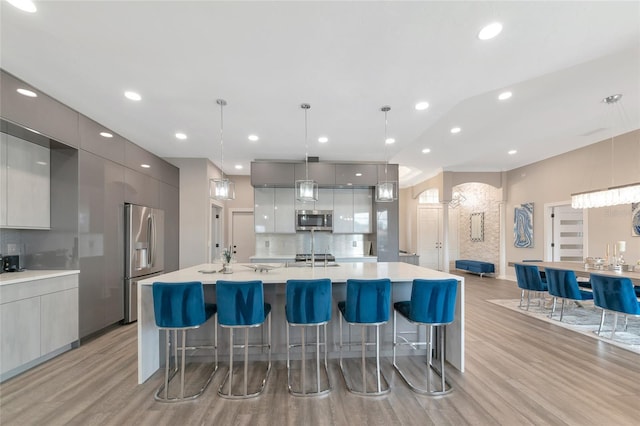 kitchen with decorative light fixtures, tasteful backsplash, a breakfast bar area, gray cabinetry, and stainless steel appliances