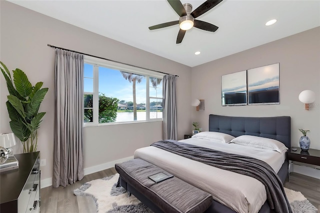 bedroom featuring a water view, ceiling fan, and hardwood / wood-style flooring