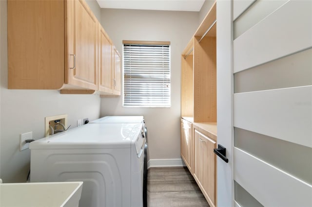 clothes washing area featuring cabinets, hardwood / wood-style flooring, sink, and washer and clothes dryer