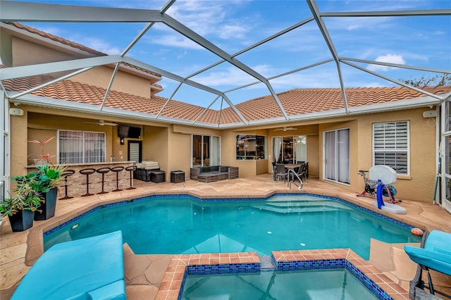 back of house with glass enclosure, a patio, ceiling fan, and exterior bar