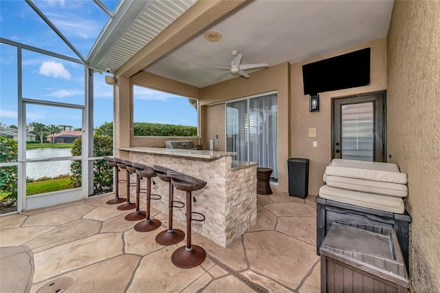 view of patio / terrace featuring a water view, ceiling fan, and a bar