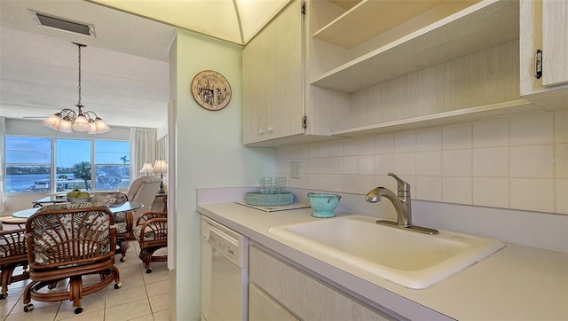 kitchen featuring sink, white dishwasher, tasteful backsplash, light tile patterned flooring, and decorative light fixtures