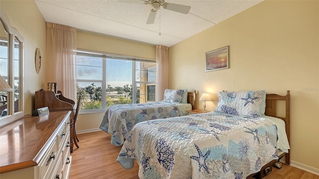 bedroom featuring ceiling fan, light hardwood / wood-style floors, and a textured ceiling