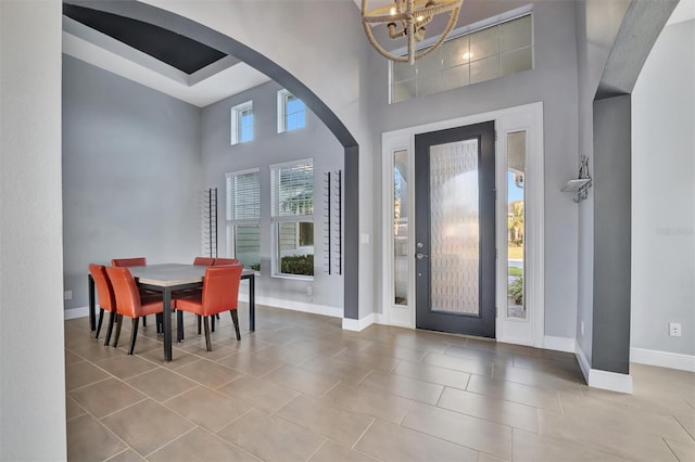 tiled entryway with a towering ceiling and a notable chandelier