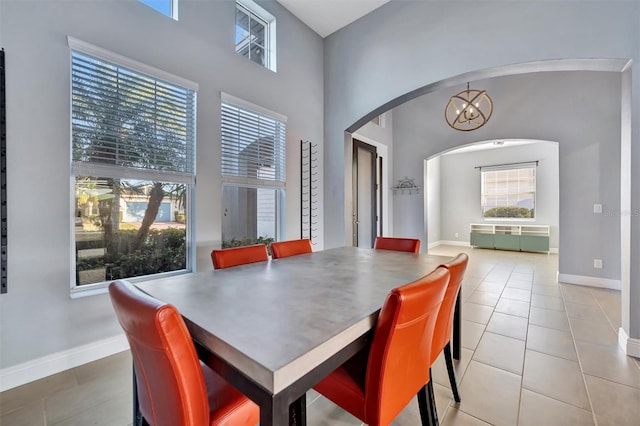 tiled dining space featuring a chandelier and a high ceiling