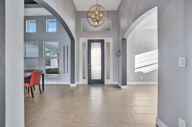 foyer entrance featuring an inviting chandelier, a high ceiling, and light tile patterned floors