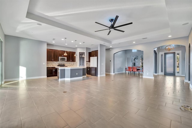 unfurnished living room featuring light tile patterned floors, ceiling fan, and a tray ceiling