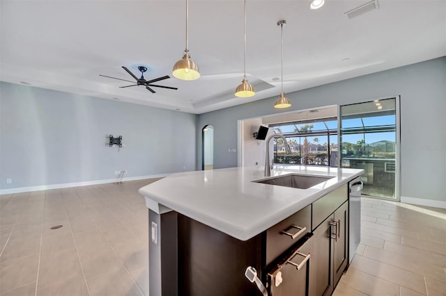 kitchen with sink, hanging light fixtures, dishwasher, an island with sink, and a raised ceiling