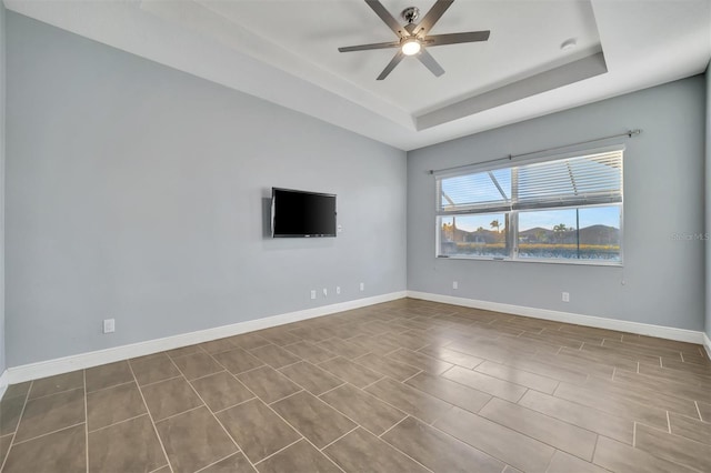 unfurnished room with ceiling fan and a raised ceiling