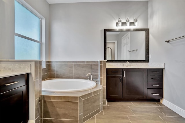 bathroom with a relaxing tiled tub, vanity, and tile patterned floors