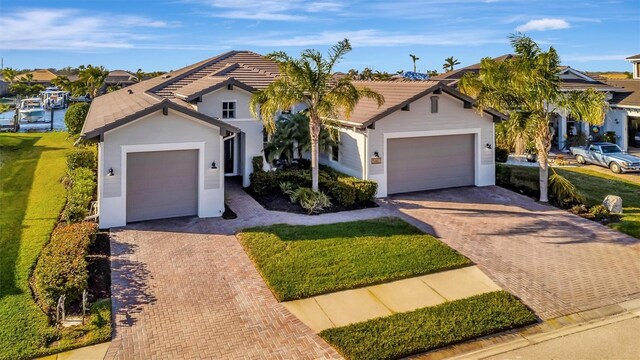 5607 Tidewater Preserve Blvd, Bradenton, FL 34208 - ranch-style home with decorative driveway, a garage, a tiled roof, a front yard, and stucco siding