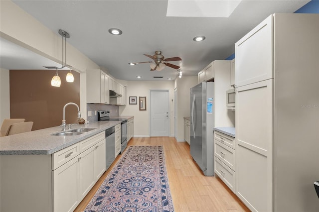 kitchen with sink, light hardwood / wood-style flooring, stainless steel appliances, white cabinets, and decorative light fixtures