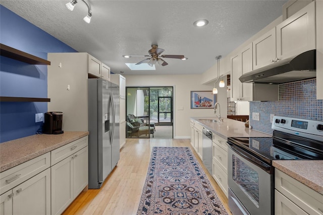 kitchen with light hardwood / wood-style flooring, appliances with stainless steel finishes, white cabinetry, decorative backsplash, and decorative light fixtures