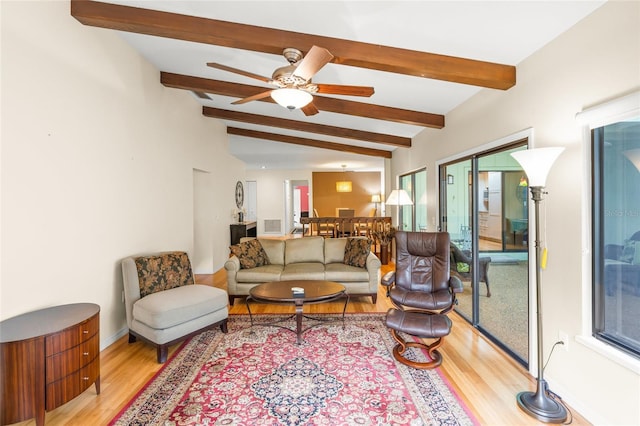 living room featuring ceiling fan, vaulted ceiling with beams, and light wood-type flooring