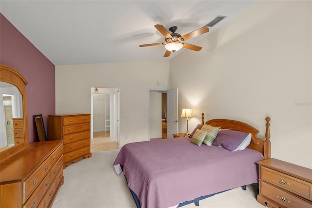 bedroom featuring ceiling fan, lofted ceiling, light carpet, and ensuite bath