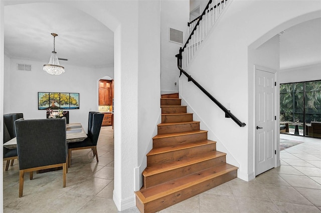 stairway featuring ornamental molding, tile patterned floors, and a chandelier