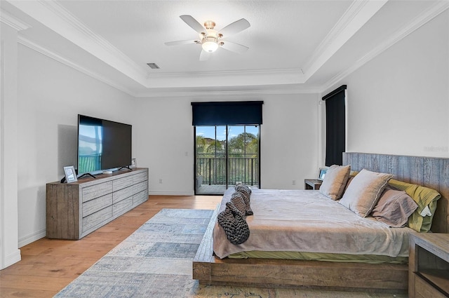 bedroom with crown molding, access to exterior, a raised ceiling, and light hardwood / wood-style floors