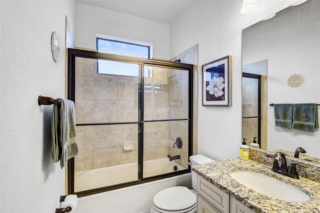 full bathroom featuring shower / bath combination with glass door, vanity, and toilet