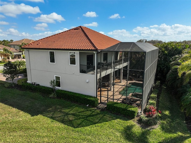 back of house with a patio, glass enclosure, and a lawn