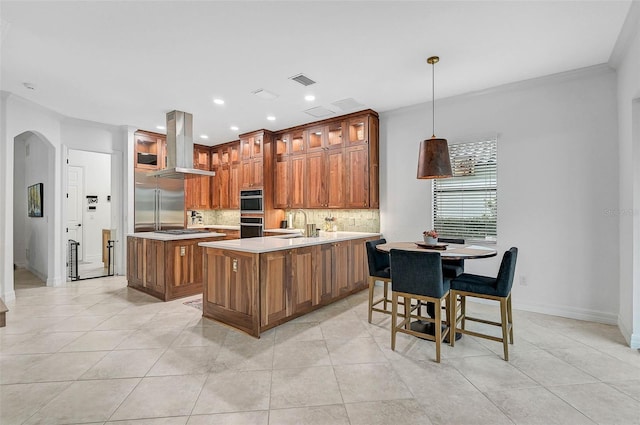 kitchen featuring sink, tasteful backsplash, decorative light fixtures, a center island, and island exhaust hood