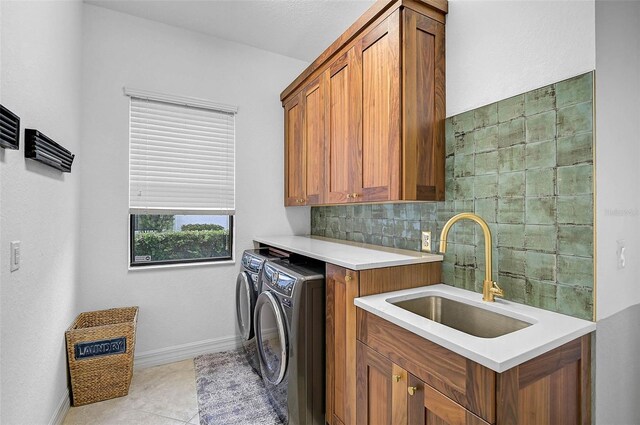 laundry room featuring sink, light tile patterned floors, washer and clothes dryer, and cabinets