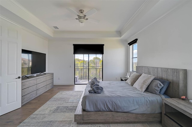 bedroom featuring ornamental molding, a raised ceiling, light hardwood / wood-style flooring, and access to outside