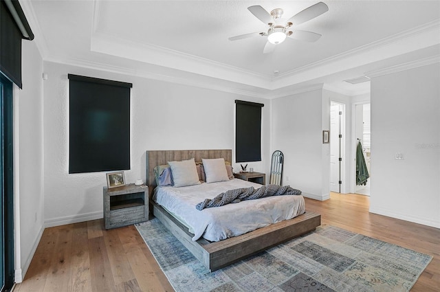 bedroom featuring crown molding, ceiling fan, a tray ceiling, and hardwood / wood-style floors