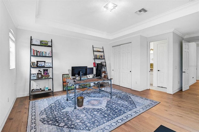 office featuring hardwood / wood-style floors, crown molding, and a raised ceiling