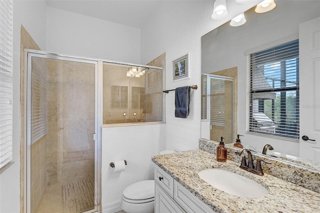 bathroom featuring vanity, a shower with shower door, and toilet