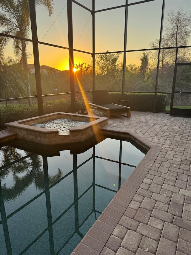 pool at dusk with an in ground hot tub and a patio area