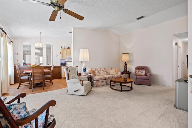 carpeted living room featuring lofted ceiling, ceiling fan with notable chandelier, and a textured ceiling