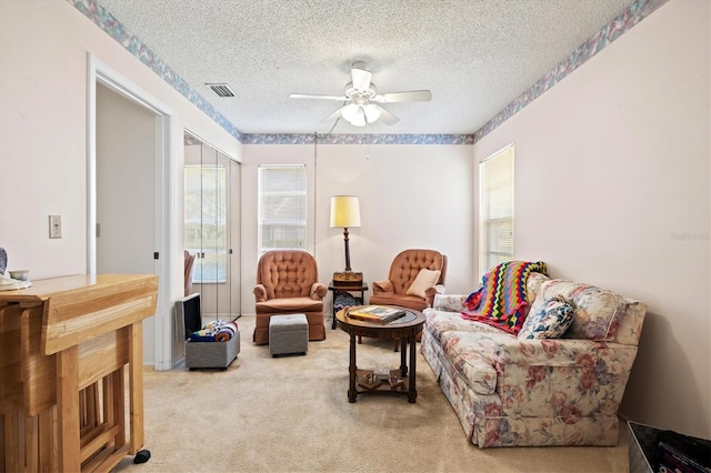 living room with ceiling fan, light colored carpet, and a textured ceiling