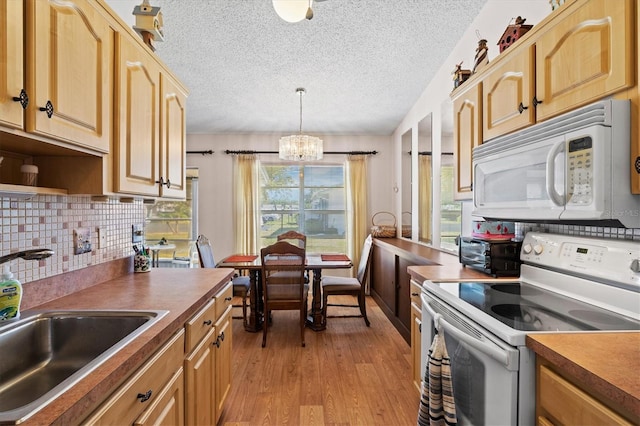 kitchen featuring decorative light fixtures, tasteful backsplash, sink, light hardwood / wood-style floors, and white appliances