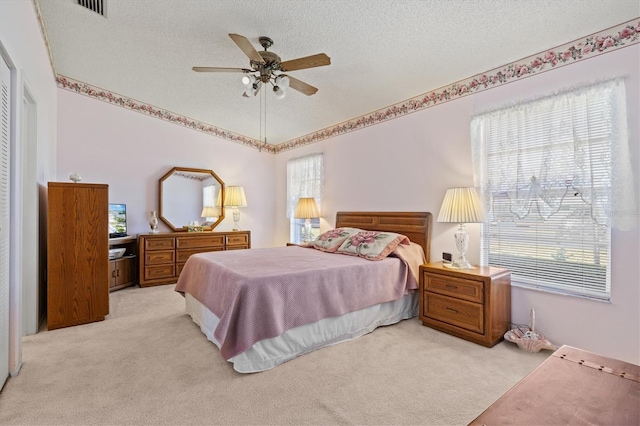 bedroom featuring light carpet, a textured ceiling, and ceiling fan