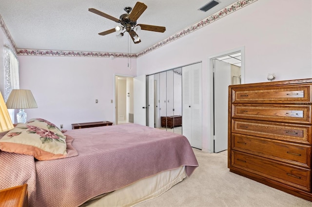 bedroom with a textured ceiling, light colored carpet, a closet, and ceiling fan