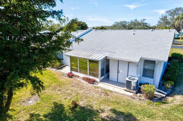 back of property with a lawn, a sunroom, and central air condition unit